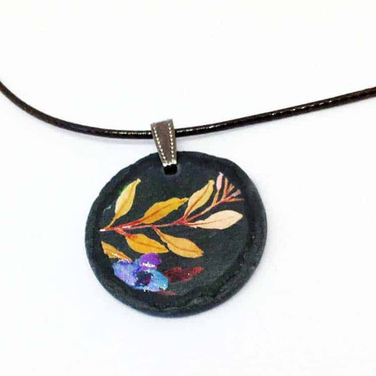 Collier en ardoise avec le thème boho floral sur fond noir - branches et fleur bleue