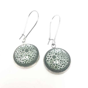 Dangling earrings with an abstract circles theme in silver on a forest green background