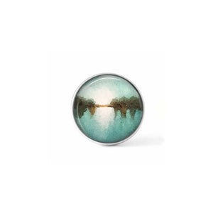 Clip-on cabochon button for interchangeable jewelry with an abstract blue, white and brown "landscape" pattern