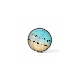 Clip-on cabochon button for interchangeable jewelry: Birds on the wire on a blue sky background